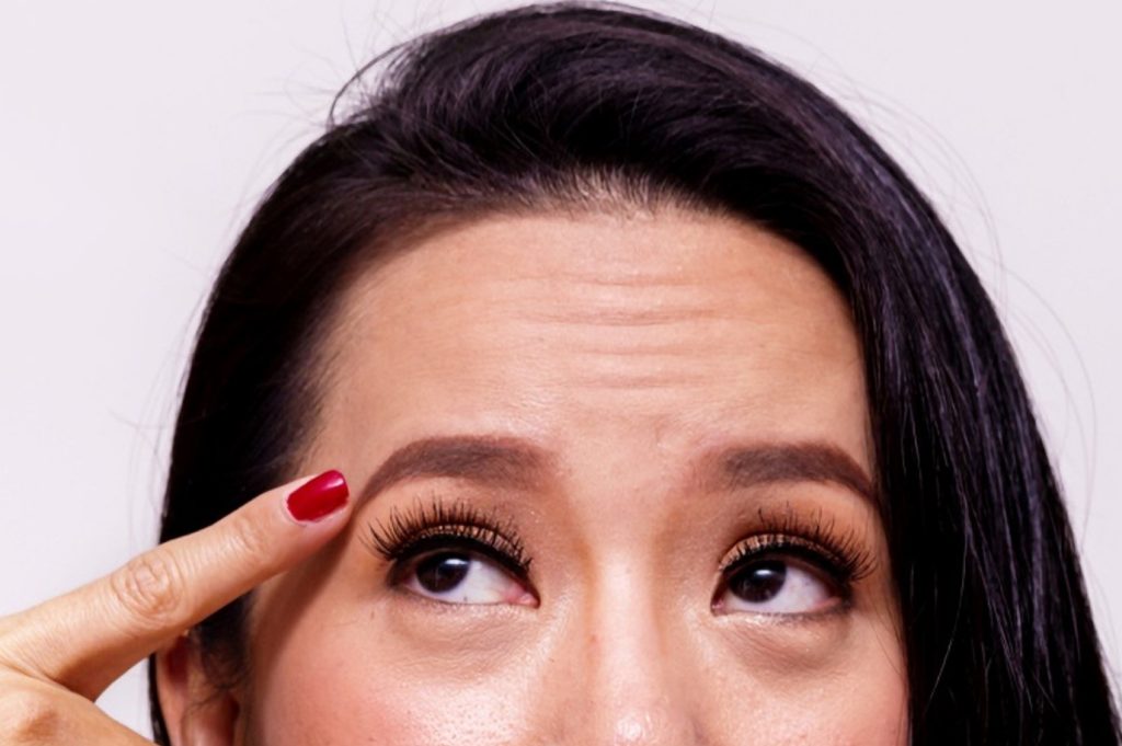 woman pointing finger to her eyebrows